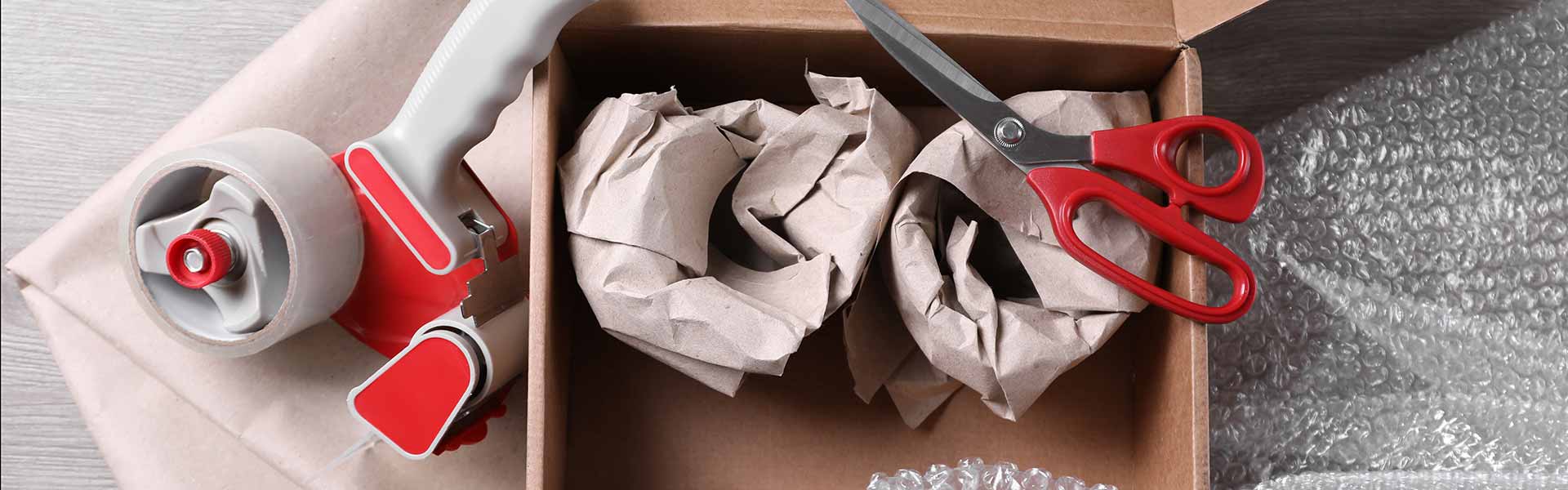 Picture of packing tape and a pair of scissors, with items being packed in a box.